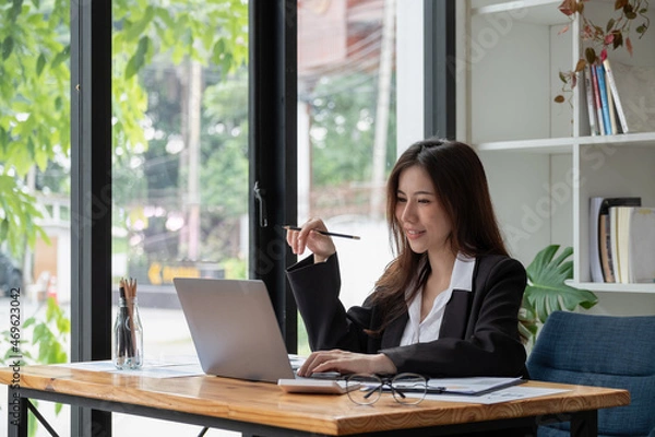 Obraz Professional asian woman at work. Shot of a financial consultant businesswoman working on laptop and doing some paperwork at the office