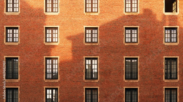 Fototapeta Old red brick wall with windows and shadow of another building at sunset
