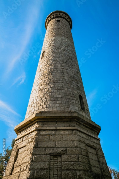 Fototapeta Myles Standish Monument on blue sky background, low angle view close-up.