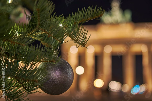 Fototapeta Germany Berlin, Christmas tree in front of illuminated Brandenburg Gate in Berlin City in the evening with dark sky, blurred  background with a beautiful bokeh, chrismas ball in front of the gate   