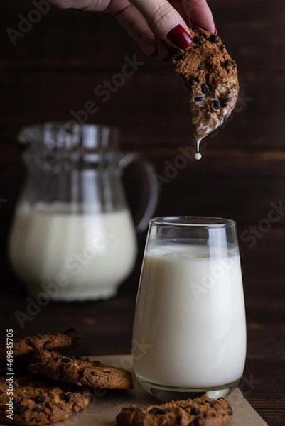 Obraz A woman's hand dips cookies in milk. Organic breakfast of pastries. Milk and cookies.