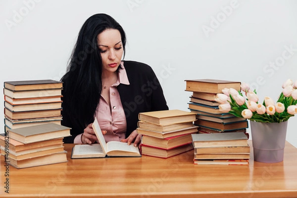 Fototapeta beautiful brunette woman in a business suit learns to read books at the table