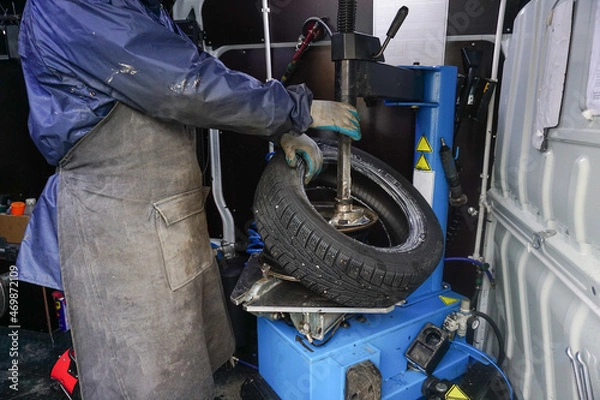 Fototapeta The process of replacing the removing the wheel disk of the car on the mobile tire fitting. the moment of separation of the tire from the disk on the equipment. Men's hands of a worker in the frame.