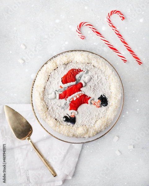 Fototapeta Christmas white cake decorated with the figure of Santa Claus on a white background with a Christmas decoration or winter holidays pastry food concept. Tpo view