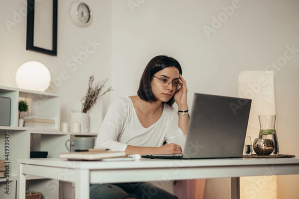 Fototapeta Woman feeling tired and stressed while using a laptop and working from home