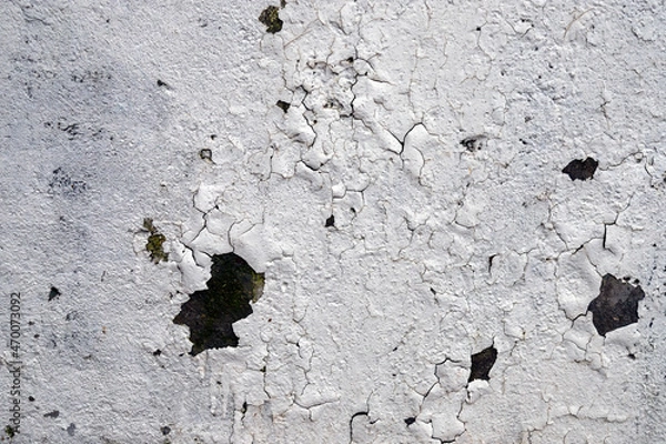 Obraz painted white wall and cracked from time with traces of rust and dirt background. Low-quality paint work.