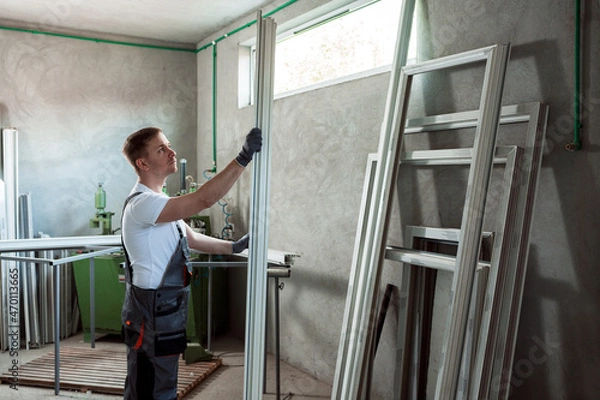 Fototapeta Worker in the workshop for making PVC doors and windows.