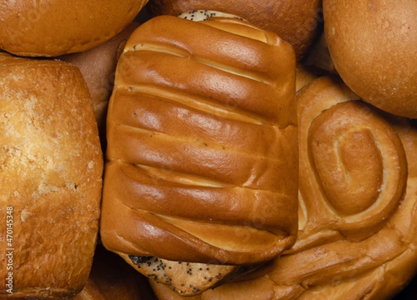 Obraz Buns and pies sweet dessert close-up. Bun with a poppy in the foreground with pretzel in the background.