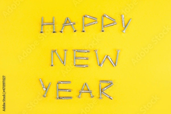 Obraz Happy New year inscription with metal hardware and screws on a yellow background.