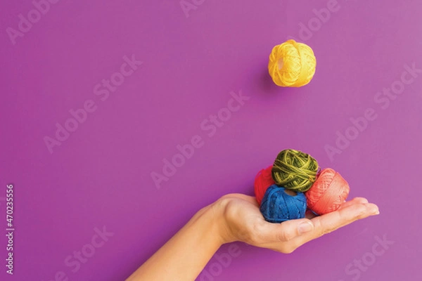 Fototapeta Variously colored colorful embroidery threads in hand on a purple background