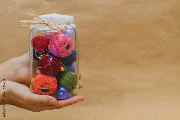 Fototapeta Multicolored threads for embroidery in a jar with lamps in hand