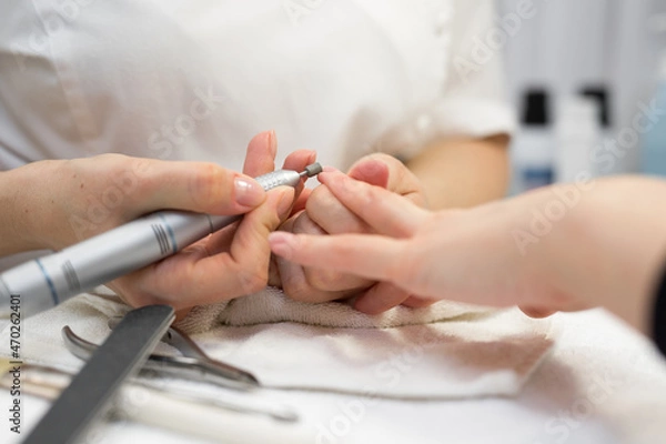 Fototapeta Close-up of manicurist doing hardware manicure to a young beautiful girl in the spa salon. Hardware manicure. Concept of body care
