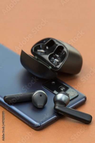 Fototapeta Wireless headphones are the phone screen on a brown background, the concept of a new purchase.