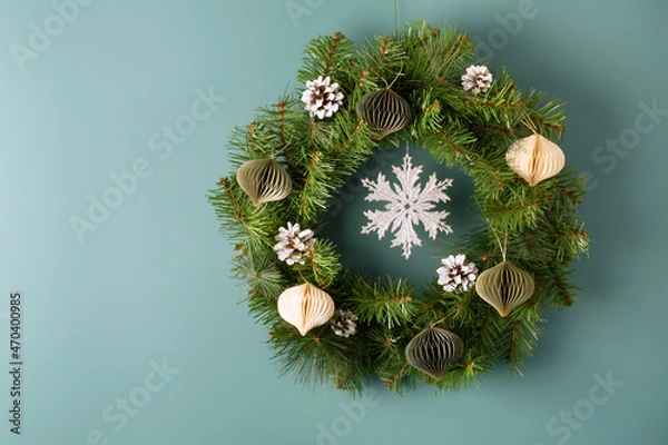 Fototapeta Christmas wreath with decoration on light blue green background, top view. Space for text
