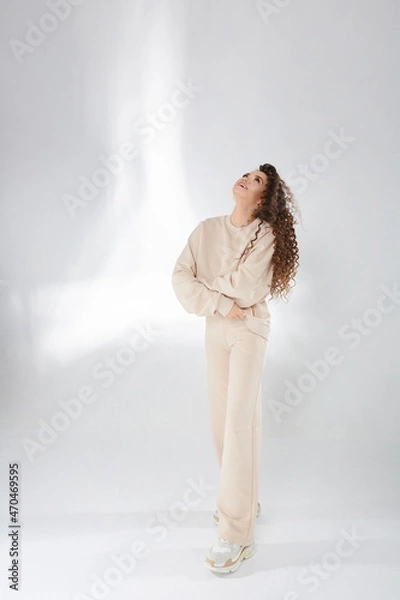 Obraz Happy model girl with afro hairstyle in a trendy sweatshirt posing with folded hands, laughing and looking up on the white background