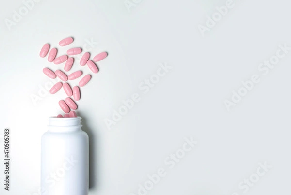 Fototapeta Pink pills in a white jar. Tablets on a white background