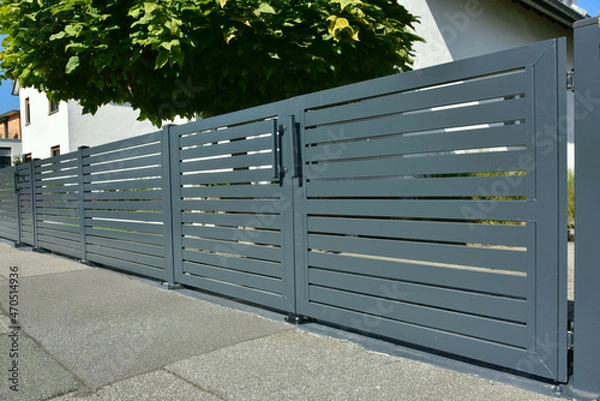 Fototapeta Beschichteter dunkelgrauer Metallzaun um den Vorgarten/Eingangsbereich eines Wohnhauses