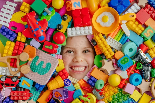 Fototapeta Funny kid lying in a very large quantity of toys