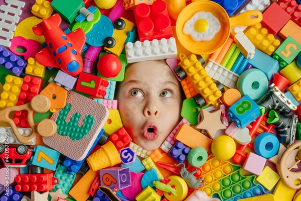 Fototapeta Funny surprised little girl lying in the chaos of toys