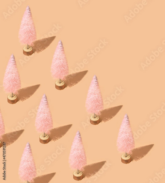 Fototapeta Christmas creative pattern made of pink Christmas trees against pastel peachy background. Winter holidays and New Year composition.