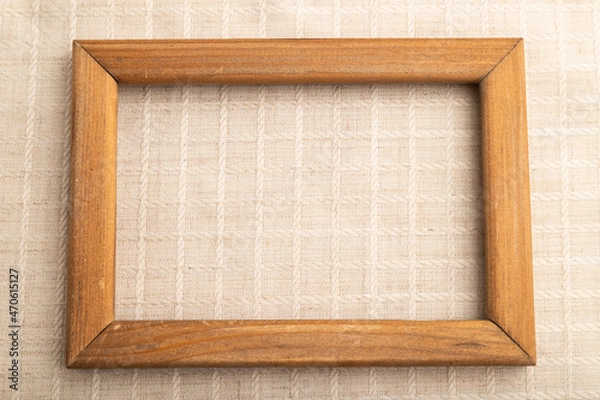 Fototapeta Wooden frame on smooth white linen tissue. Top view, natural textile background.