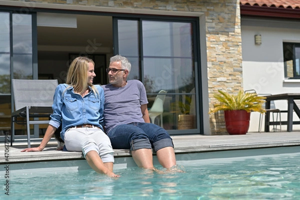Fototapeta Middle-aged couple enjoying time by private pool