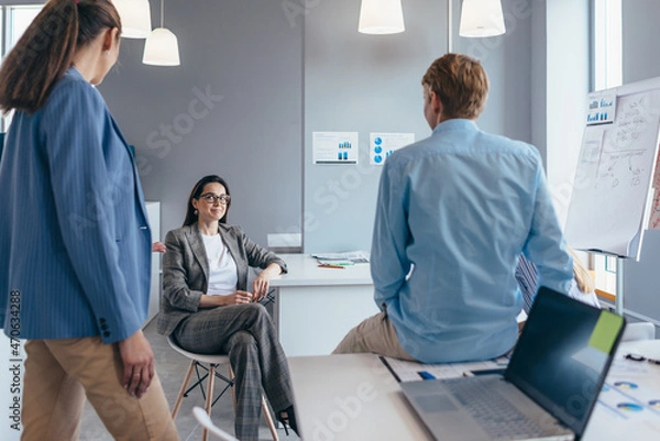 Fototapeta Group of employees are gathering informally in the office and chatting