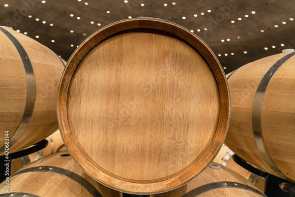 Fototapeta New oak barrel with stainless steel rings in a winery for making wine. End view. Advertising, copy  space