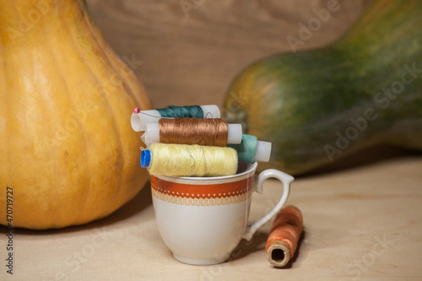 Obraz Spools of colorful thread in a coffee cup with pumkins