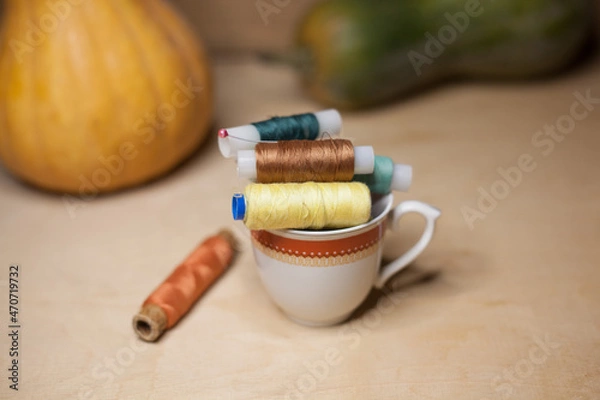 Obraz Spools of colorful thread in a coffee cup with pumkins