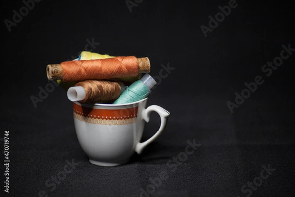 Obraz Spools of colorful thread in a coffee cup