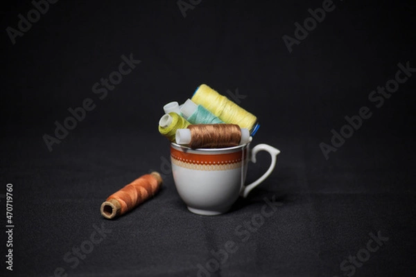 Obraz Spools of colorful thread in a coffee cup
