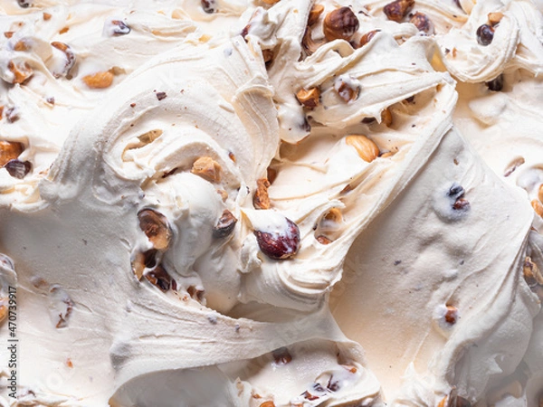 Fototapeta Frozen Hazelnut flavour gelato - full frame detail. Close up of a white creamy surface texture of Ice cream filled with pieces of nuts.