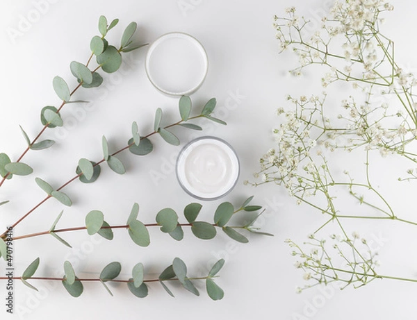 Fototapeta white face cream on a white background with eucalyptus and dried flowers