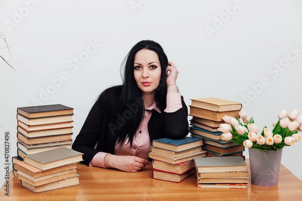 Fototapeta beautiful brunette woman in a business suit learns to read books at the table