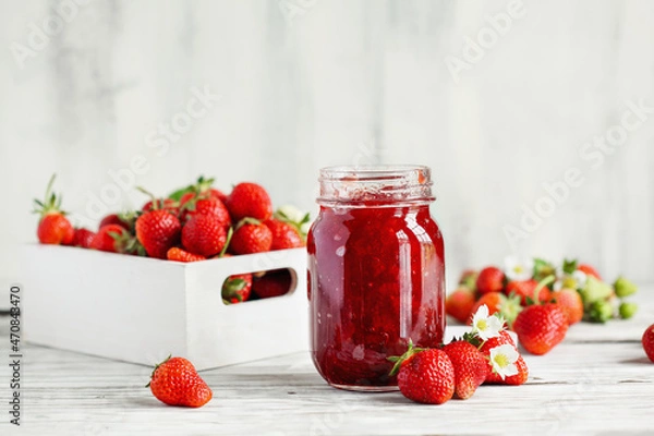 Fototapeta Homemade strawberry preserves or jam in a mason jar surrounded by fresh organic strawberries. Selective focus with blurred foreground and background.