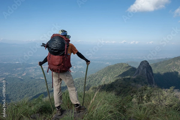 Fototapeta A trekker carried a backpack with a black trash bag hung from the top of the mountain.