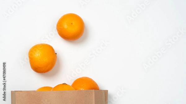 Fototapeta Bright ripe orange oranges in the package on a white background. View from above.