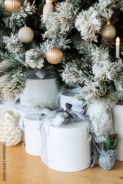 Obraz Christmas gifts under a snowy tree, beautiful white boxes. Gift for the new year. Beautiful box with a bow.