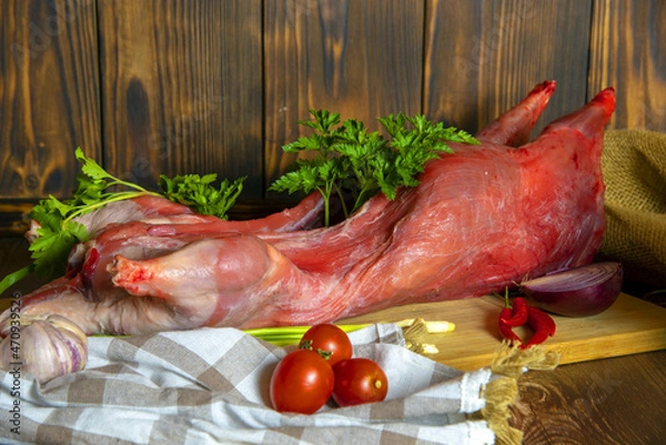 Fototapeta Nutria carcass on a wooden cutting board with fresh vegetables and herbs.