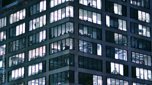 Fototapeta Corporate building at night - business concept. Glass wall office building .Modern office windows of skyscraper glowing at night.