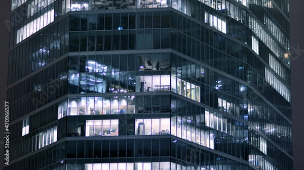 Fototapeta Corporate building at night - business concept. Glass wall office building .Modern office windows of skyscraper glowing at night.