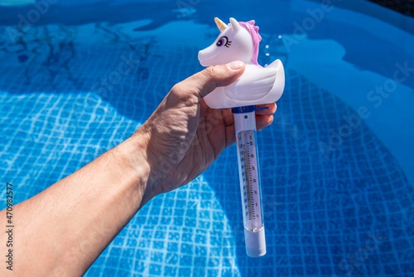 Fototapeta Checking the temperature of the swimming pool water with a funny thermometer. Unicorn pool thermometer