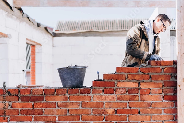 Fototapeta man building brick wall, bricklayer