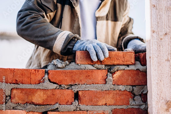 Fototapeta man building brick wall, bricklayer