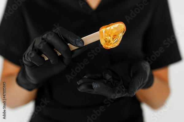 Fototapeta Redhead sugaring master in a black robe putting some sugar on her hands