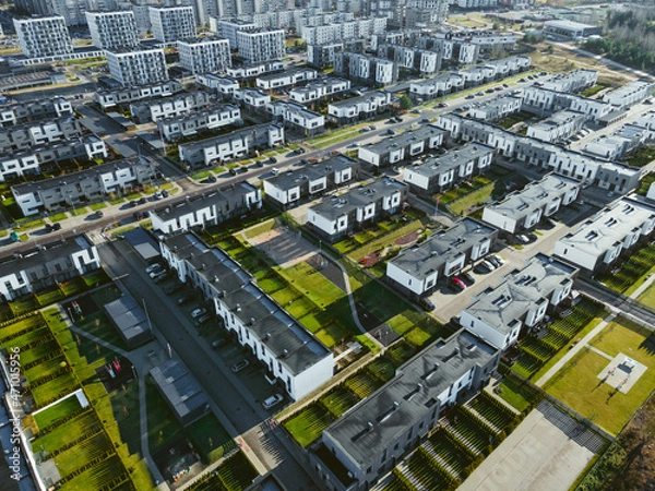 Fototapeta Aerial photo of the modern residential district in growing europe city. Block flats and cottages with yards and greenery. City expansion, capitalism. 