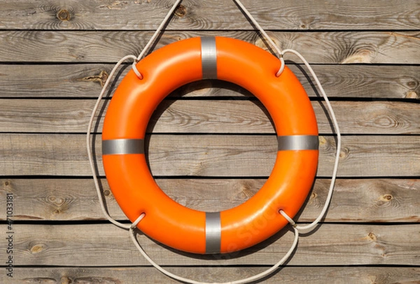 Fototapeta Orange life buoy hanging on wooden wall