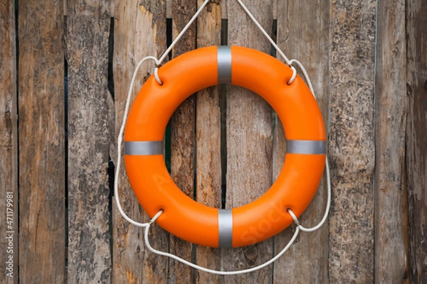 Fototapeta Orange life buoy hanging on wooden wall