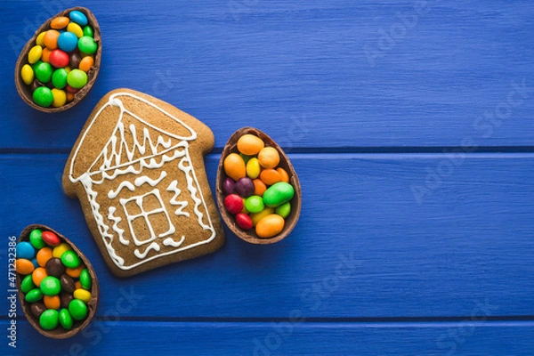 Obraz Gingerbread and colored sweets on a blue  wooden background.  Place for text or logo.